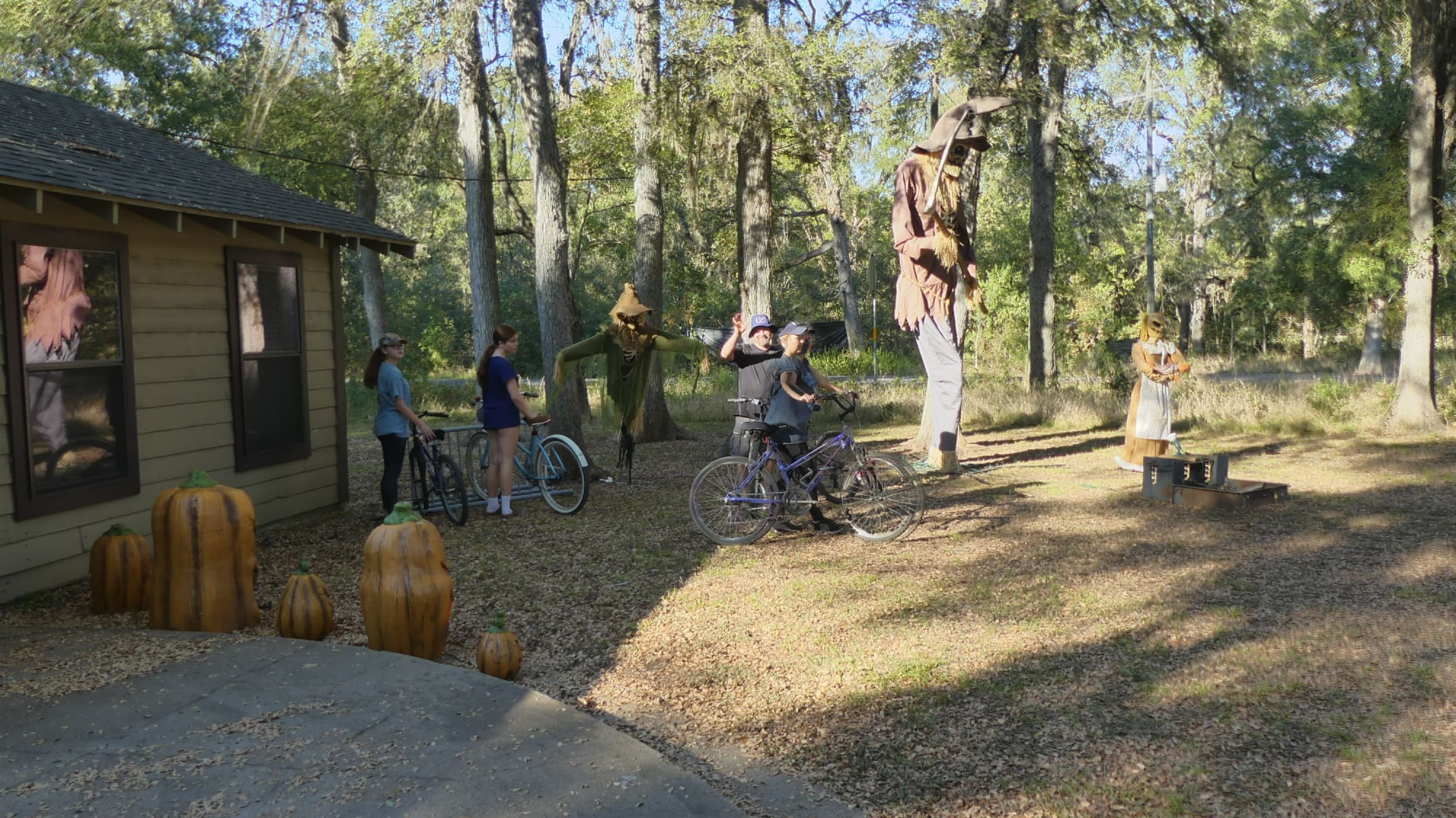 family with bicycles in front of a building with scarecrow decorations